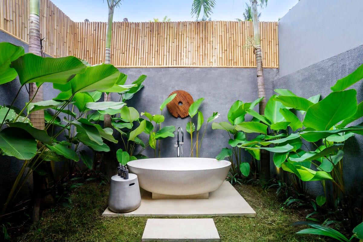 Private modern outside bathtub surrounded by greenery