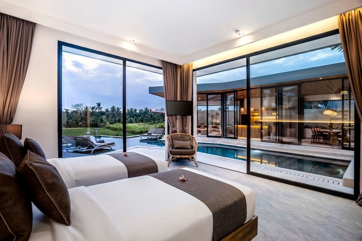 Twin bedroom with a view of the pool and outside area at nighttime