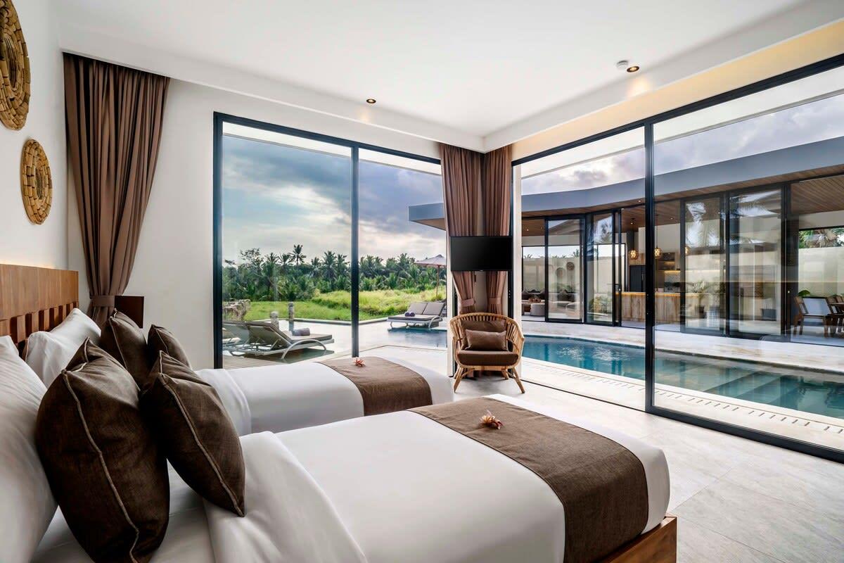 Twin bedroom with a view of the pool and outside area during daytime