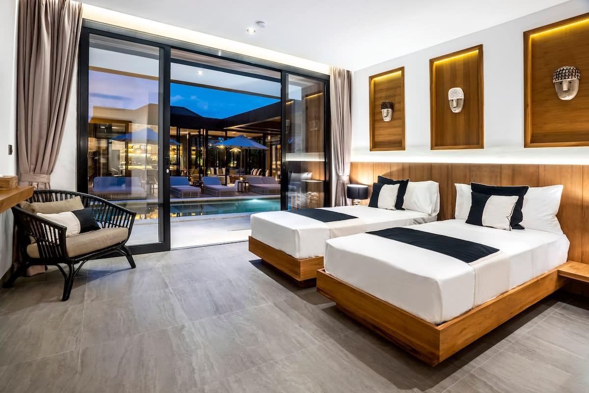 Twin bedroom with a view of the pool and outside area at nighttime