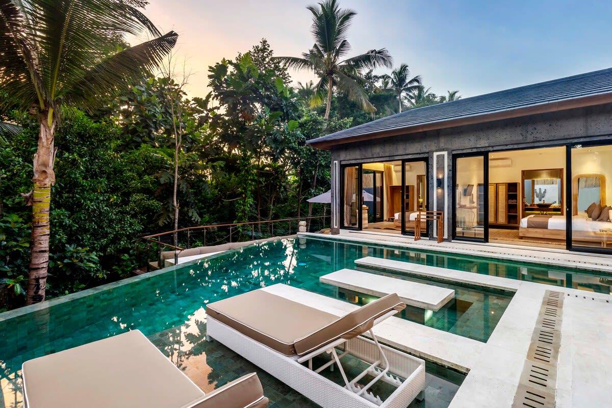 View of the villa’s pool and lounging area with a jungle background