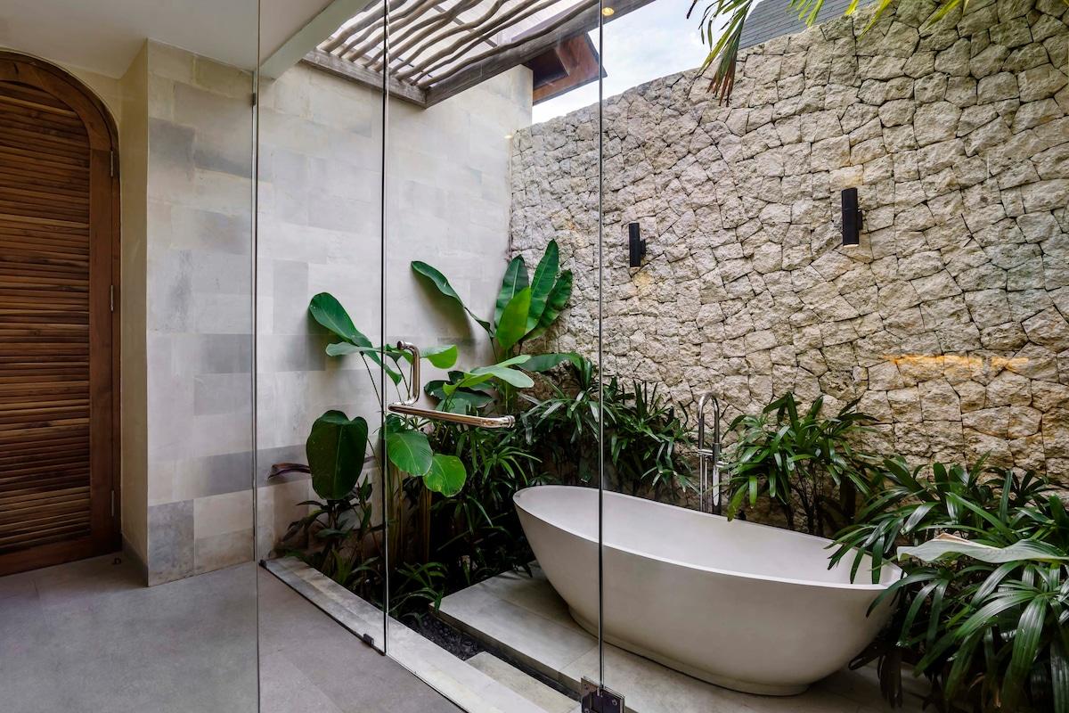 Secluded outside bathtub surrounded by beautiful greenery and a stone wall